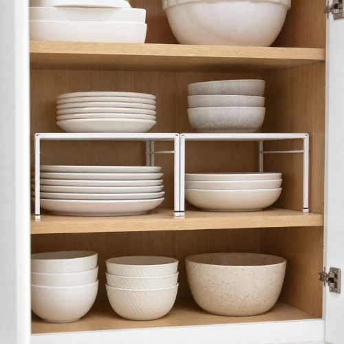 kitchen cabinet interior with stackable shelf risers organizing plates and bowls on two levels